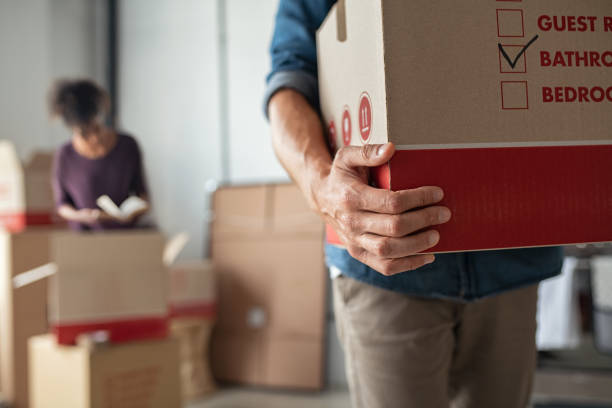 Hands holding cardboard box during relocation Closeup of man hand holding cardboard at new home. Young man unpacking boxes in new apartment. Man hand carrying carton box while relocating with his girlfriend. moving stock pictures, royalty-free photos & images